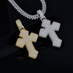 Two cross-shaped pendants, one gold and one silver, on a dark background.