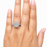 Hand displaying a 2.00 CTW DEW Oval Moissanite Halo Engagement Ring | GRA Certified 925 Silver on the ring finger, showcasing the oval-shaped stone surrounded by a halo of smaller stones on a silver band.
